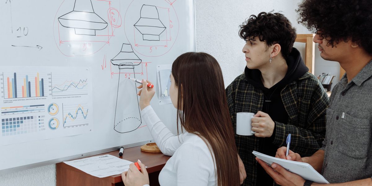 A group of engineers and architects actively planning complex system architecture on a whiteboard.
