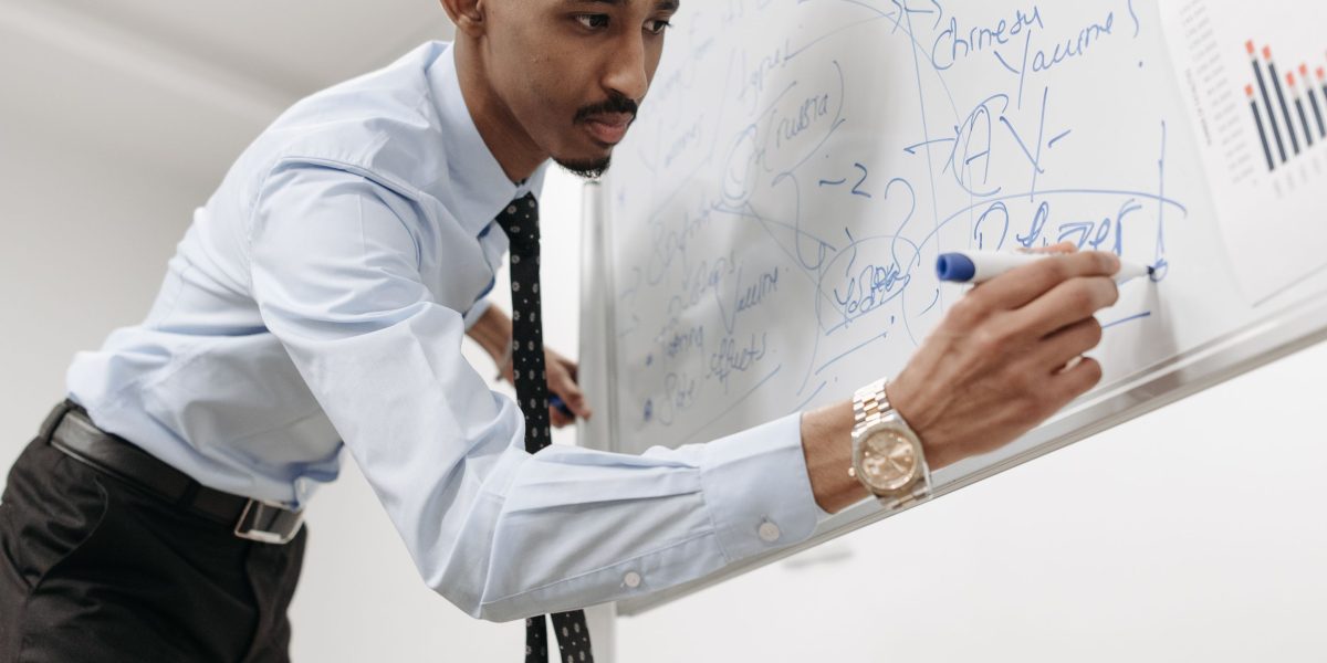 A person actively writing notes or sketching ideas on a whiteboard, symbolizing active learning, planning, and project development.