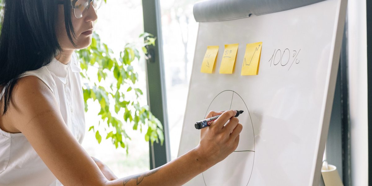 A person actively writing on a whiteboard, symbolizing the process of designing and structuring a learning path.