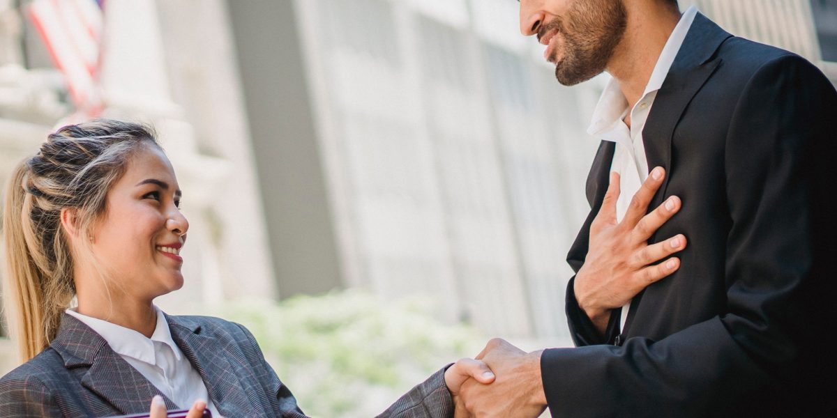 A diverse group of business professionals shake hands outdoors, symbolizing successful partnerships and collaboration across industries.